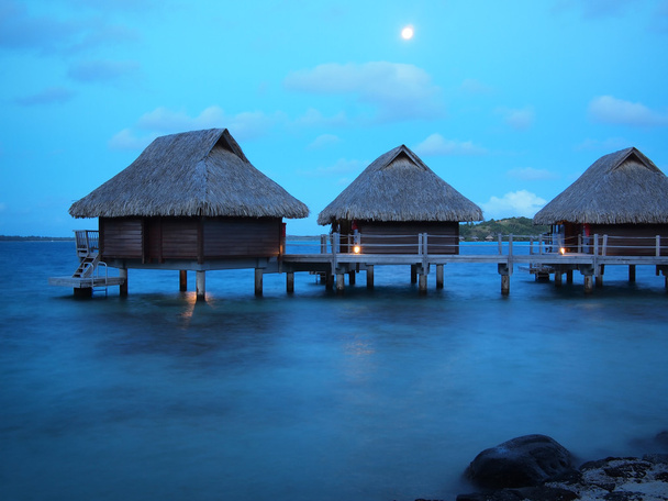 Techo de paja bungalows sobre el agua a la hora azul
 - Foto, imagen