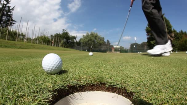 Golfer schlug den Ball auf dem Putting Green ins Loch; Sommersonniger Tag, selektiver Fokus auf den Ball - Filmmaterial, Video