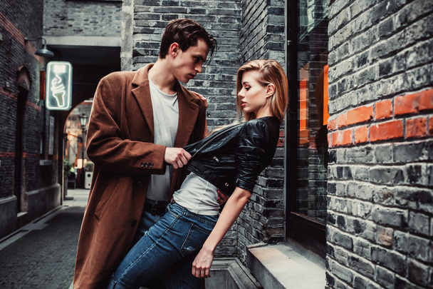 Mladý módní muž a žena pózuje v cihlové zdi ulice - Fotografie, Obrázek