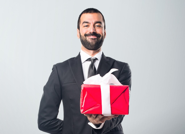 Empresario sosteniendo un regalo
 - Foto, Imagen