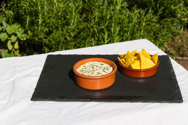 Aubergine dip in ceramic bowl with tortilla chips. Outdoors on s - Photo, Image