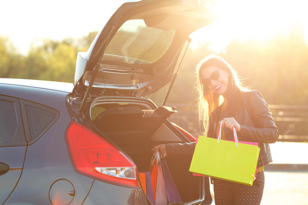 Woman putting her shopping bags into the car trunk - Foto, Bild