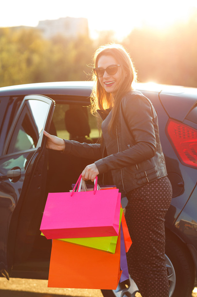Усміхається жінка кавказька, поклавши її сумками в машину - Фото, зображення
