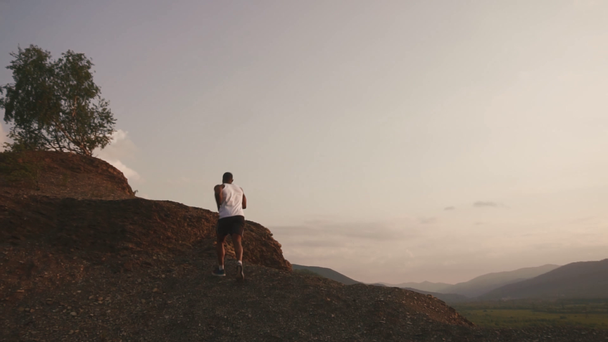 Handsome african american muscular bodybuilder jogging outdoor. Rocky mountain landscape background - Filmagem, Vídeo