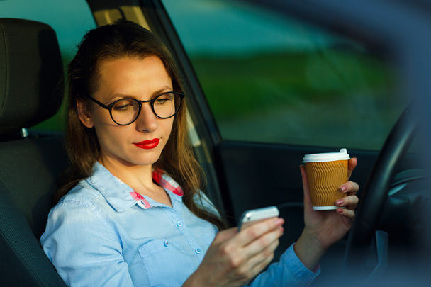 Businesswoman sending a text message and drinking coffee while d - Photo, Image