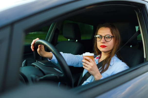 Young woman with coffee to go driving her car - Photo, Image