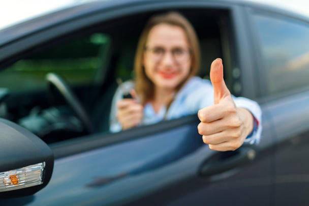 Jovem mulher feliz sentado em um carro com as chaves na mão e
 - Foto, Imagem