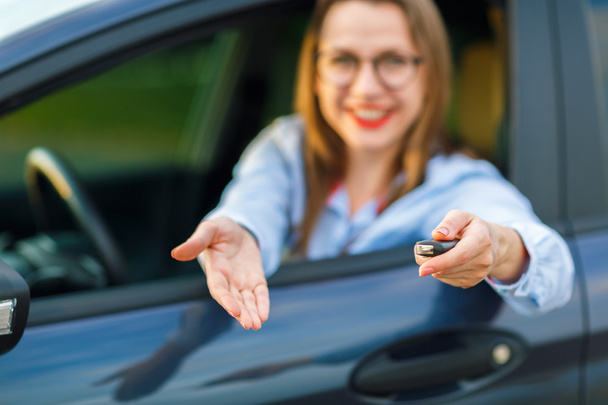 Jovem mulher bonita sentada em um carro com as chaves na mão
 - Foto, Imagem