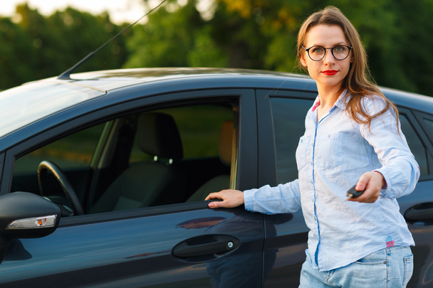 Nuori nainen seisoo lähellä autoa avaimet kädessä
 - Valokuva, kuva