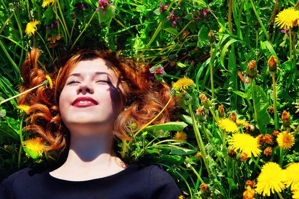 girl with red hair lying on the field of dandelions - Foto, Bild