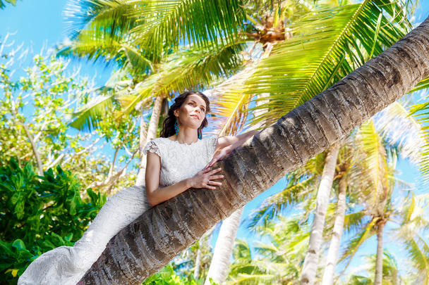 Young beautiful bride in white wedding dress on the palm tree on - Zdjęcie, obraz