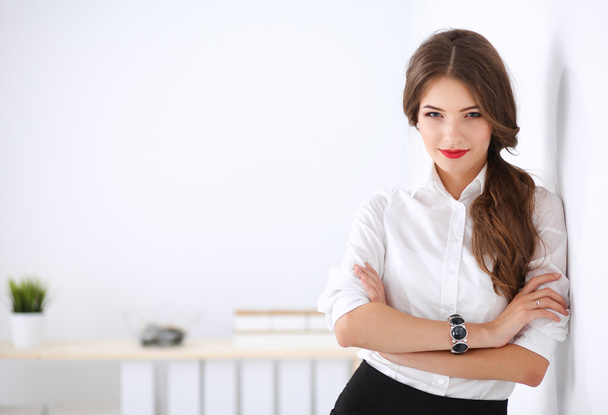 Attractive businesswoman standing near wall in office - Φωτογραφία, εικόνα