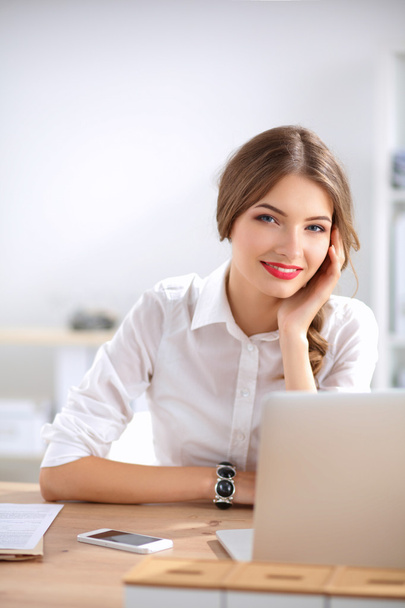 Attractive businesswoman sitting on desk in the office - Фото, изображение