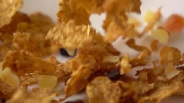 Super slow motion close shot of corn flakes with fruits and raisin fall on plate - Video