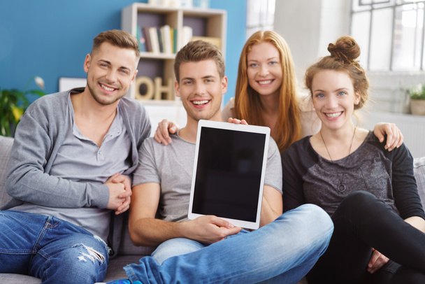 Seated friends hold up computer tablet and smile - 写真・画像