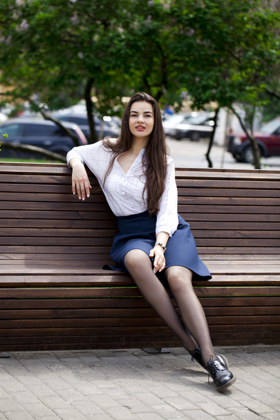 Young beautiful girl sitting on a bench in the summer park - Foto, afbeelding