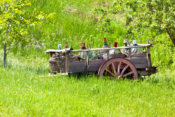 ワインのボトルと古い素朴なワゴン - 写真・画像