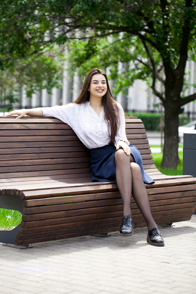Young beautiful girl sitting on a bench in the summer park - Foto, Imagem