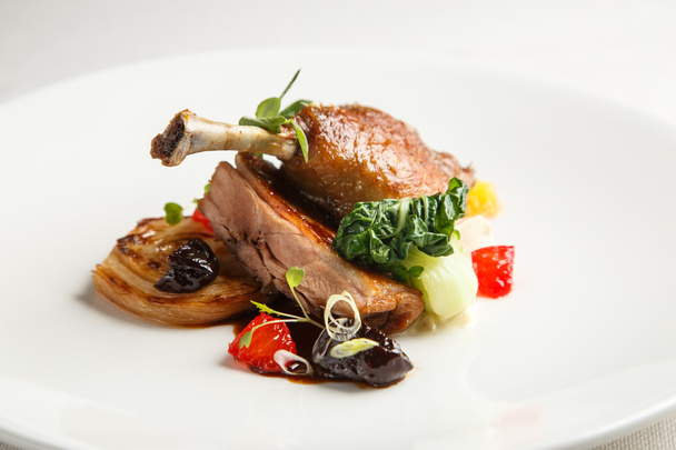 Well-browned and crisp duck confit with roast fennel, citrus fruit  prune sauce. Roasted  leg. White dish - Photo, Image