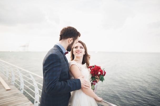 Married wedding couple standing on a wharf over the sea - Fotó, kép