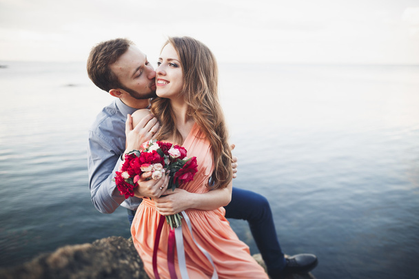 Wedding couple kissing and hugging on rocks near blue sea - Fotografie, Obrázek