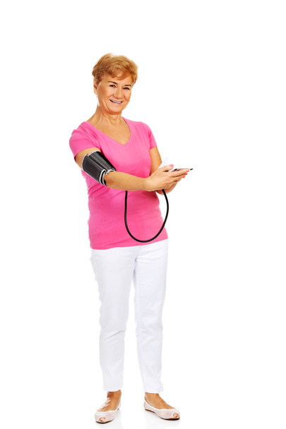 Mulher idosa sorridente medindo a pressão arterial
 - Foto, Imagem