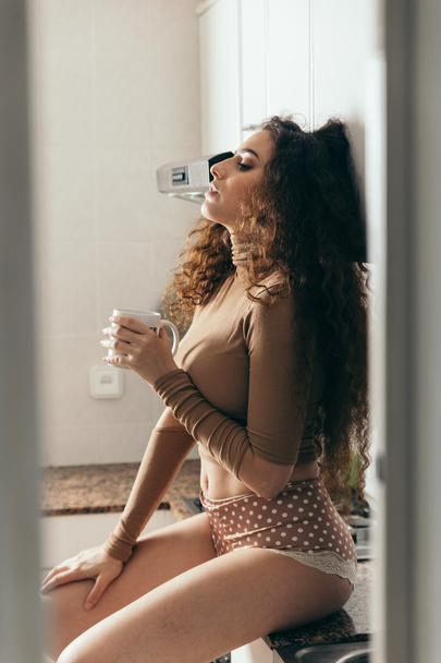 Sexy woman wearing lingerie and holding a coffee cup. - Fotó, kép