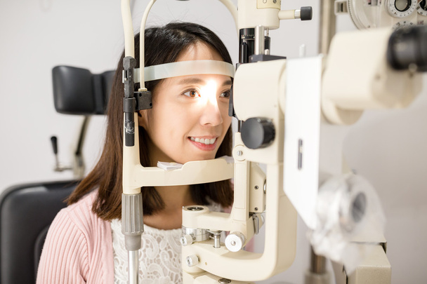 Γυναίκα που ψάχνει σε οφθαλμοσκόπιο - Φωτογραφία, εικόνα