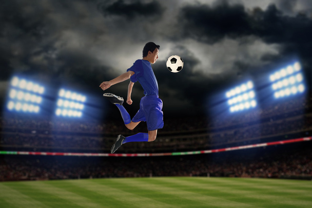 Jugador de fútbol jugando una pelota por la noche
 - Foto, Imagen