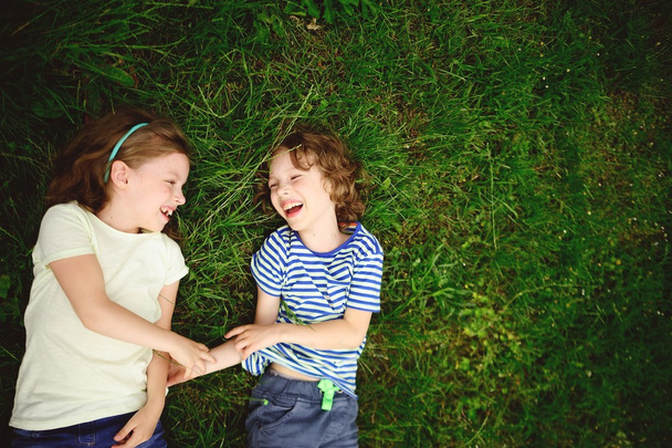 Dvě veselé děti leží na zelené trávě. - Fotografie, Obrázek