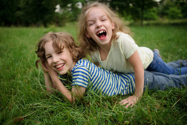 Brat i siostra zabawy na zielony trawnik. - Zdjęcie, obraz
