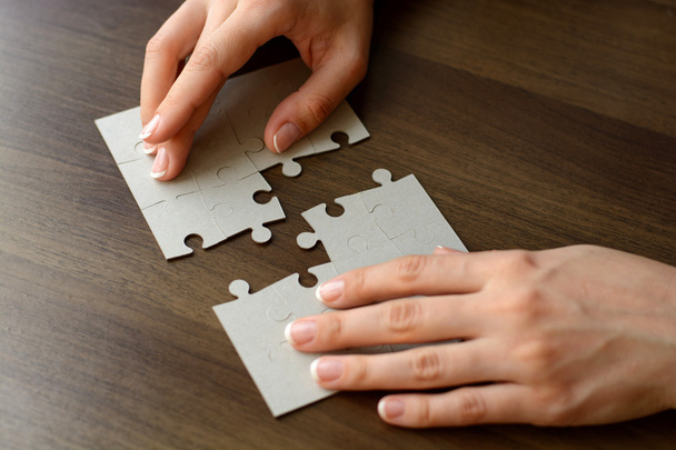 Female hands on a wooden office desk pick puzzle - Photo, Image