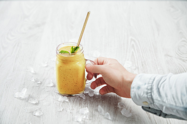 Man hand takes smoothie from mango, pineapple, passion - Photo, Image