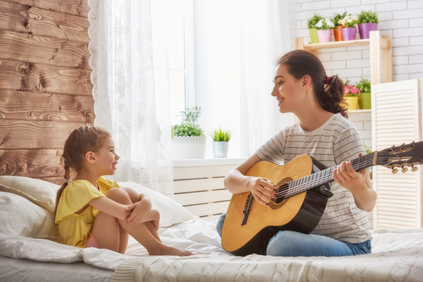 Mother and daughter playing guitar - Photo, image