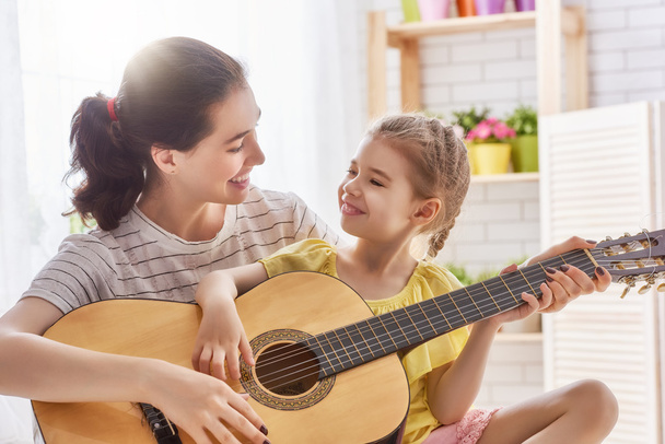 Mother and daughter playing guitar - Фото, зображення