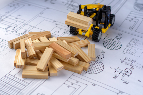 Іграшкова будівельна машина будуємоделювання будинку з дерев'яних блоків (панелей) на кресленнях
. - Фото, зображення