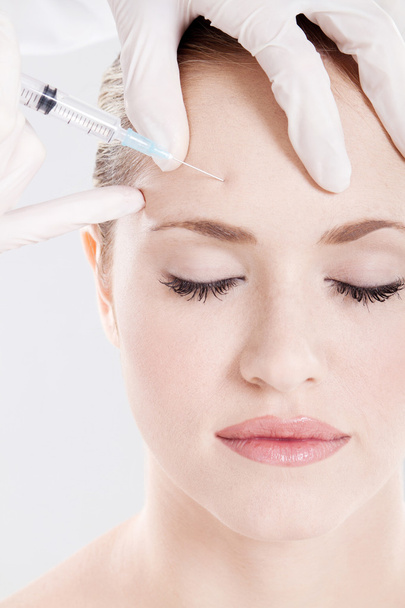 Doctor giving injection on woman's forehead - Valokuva, kuva