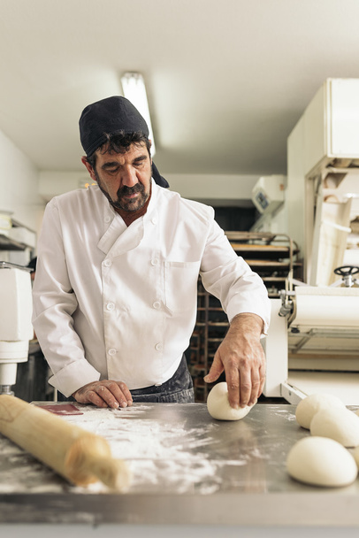 Baker kneading dough in a bakery. - Fotoğraf, Görsel