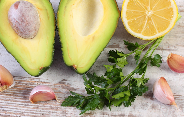 Avocado, garlic, lemon and parsley on wooden background, ingredient of avocado paste or guacamole, healthy food and nutrition - Фото, изображение