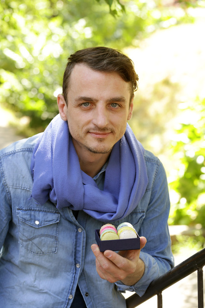 joven guapo con una caja de macarrones franceses
  - Foto, imagen