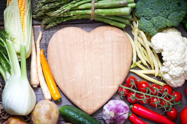 Fresh vegetables and empty heart shaped cutting board - Fotoğraf, Görsel