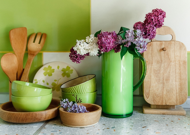 Kitchen  Ceramic and Wooden Tableware,Bouquet of Lilac in the Green Plastic Pitcher. - Photo, Image
