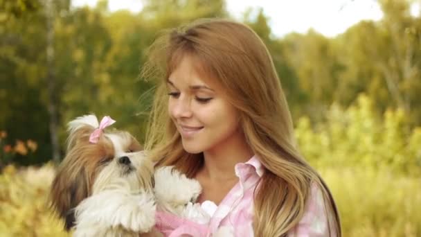 Retrato de mulher sorridente muito jovem segurando pequeno cachorro fofo, contra o fundo do parque verde de verão
 - Filmagem, Vídeo