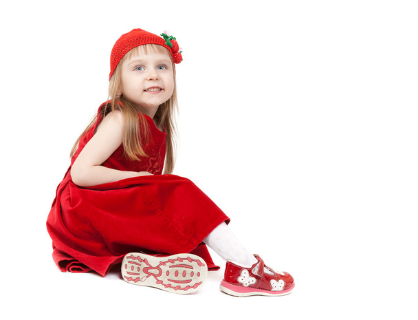 Beautiful four-year-old girl in a red dress and hat sitting on w - Zdjęcie, obraz