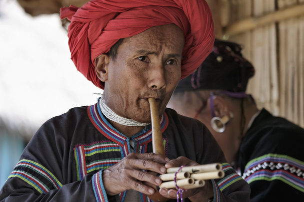 thailand, chiang mai, karen long neck hill tribe village (kayan lahwi), karen man in traditionellen trachten, die eine flöte spielen - Foto, Bild