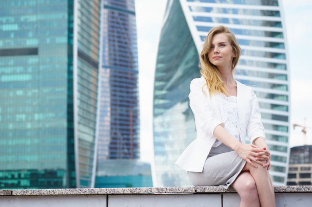 Young woman sitting in front of city buildings. - Foto, Imagem
