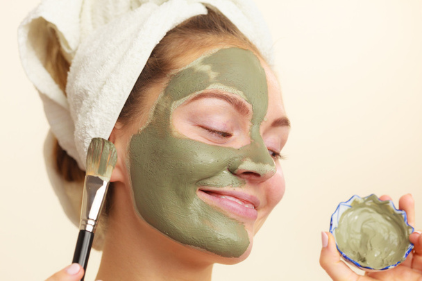 Woman applying with brush clay mud mask to her face  - Foto, afbeelding