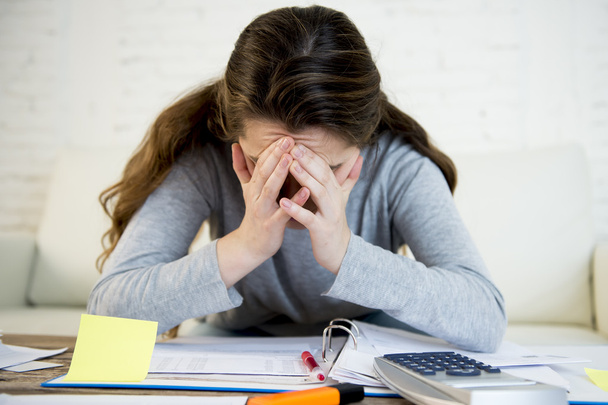 young worried woman suffering stress doing domestic accounting paperwork bills - Foto, afbeelding