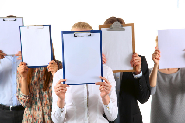 Team of businesspeople holding a folders near face isolated on white background - Foto, afbeelding