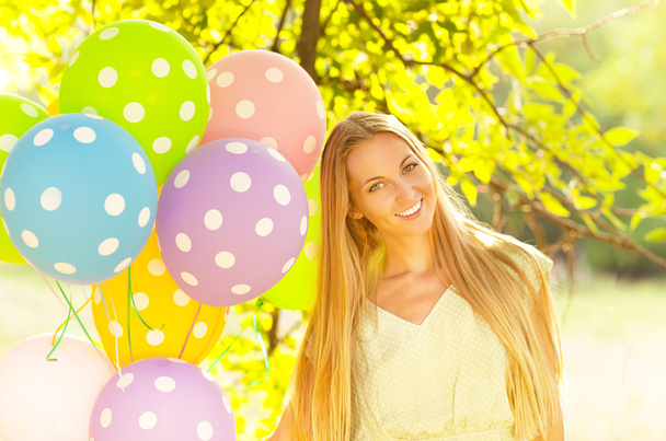 Mujer feliz con globos de lunares de colores
 - Foto, imagen